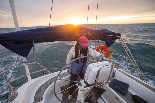 Uomo in piedi al timone di yacht a vela in mare durante il tramonto — Foto Stock