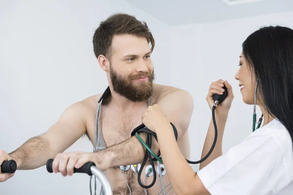 Dokter van meten van de bloeddruk van de patiënt met elektroden op Bo — Stockfoto