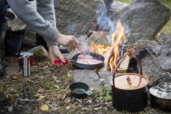 Homem cozinhar comida sobre fogueira no acampamento — Fotografia de Stock