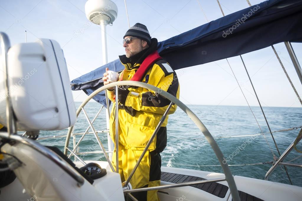 Man Holding Coffee Cup While Standing At Helm Of Yacht