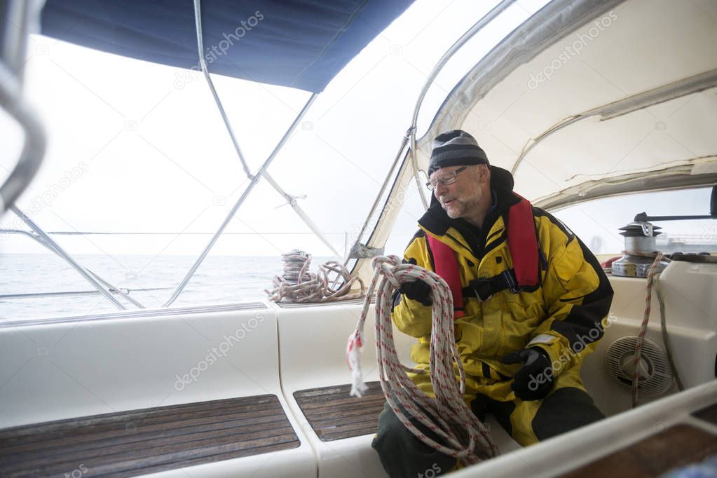 Man Holding Rope While Sitting On Yacht