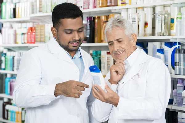 Apotheker schaut sich Shampoo-Flasche in Apotheke an — Stockfoto