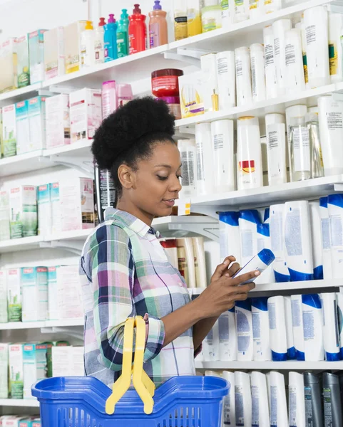 Kobiece klienta trzymając butelkę szamponu przez półki — Zdjęcie stockowe