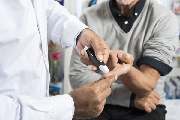 Доктор проверяет уровень сахара у старшего пациента с глюкометром — стоковое фото