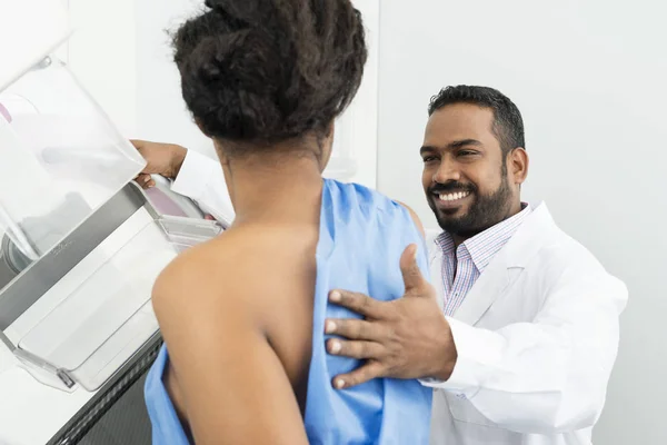 Médico sonriente que asiste al paciente que se somete a prueba de rayos X de mamografía — Foto de Stock