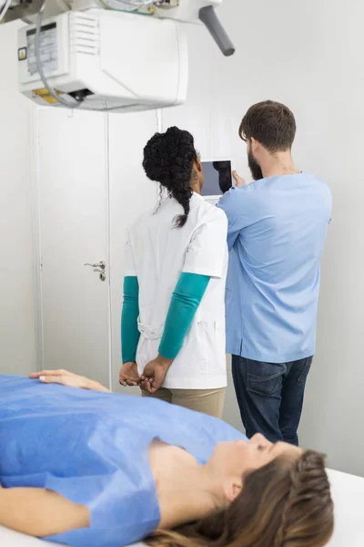 Radiologiste utilisant la tablette numérique avec la femme couchée au premier plan — Photo