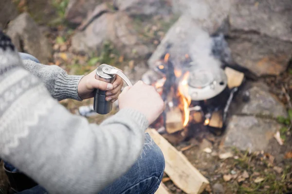 Mann mahlt Kaffee am Lagerfeuer auf Campingplatz — Stockfoto