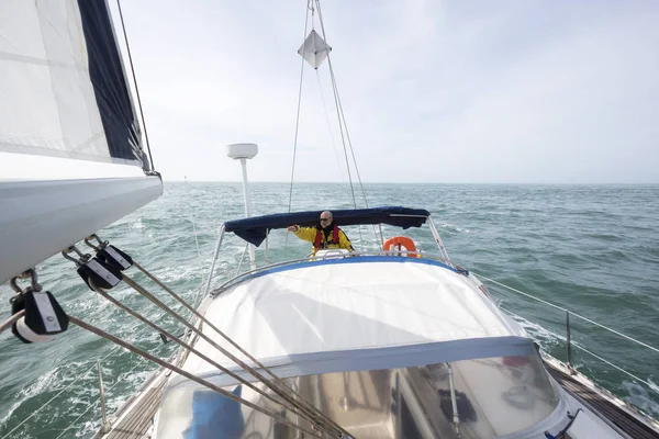 Man Steering barca a vela di lusso in mare il giorno soleggiato — Foto Stock