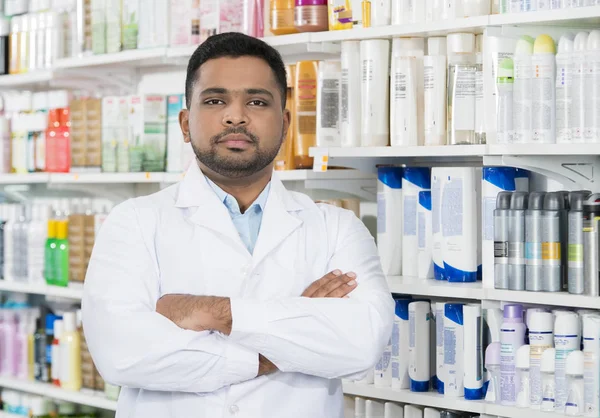 Pharmacien bras croisés contre des étagères en pharmacie — Photo