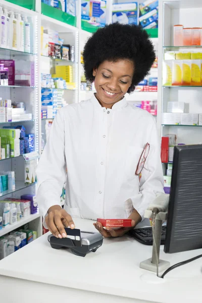Fêmea Farmacêutica Swiping Cartão de Crédito Enquanto Segurando Produto — Fotografia de Stock