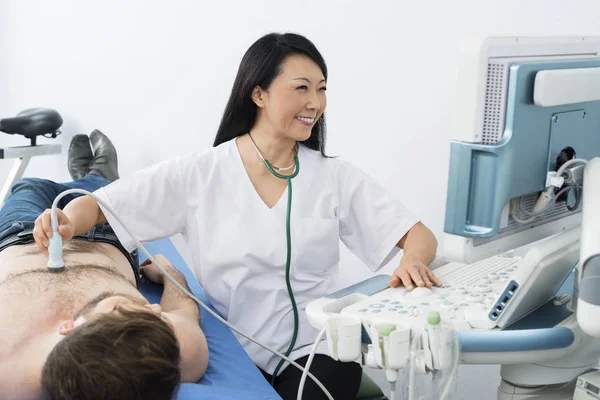 Feliz médico realizando una prueba de ultrasonido en el paciente — Foto de Stock