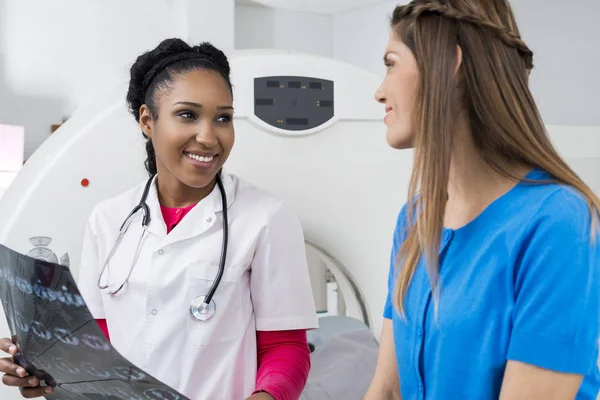 Ärztin hält Brust-Röntgen, während sie Patientin anschaut — Stockfoto
