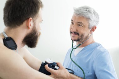Doktor hastanın kan basıncını ölçüyor.