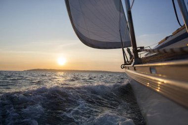 Gün batımı sırasında denizde yelken tekne yelken