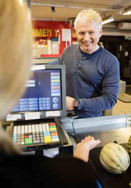 Customer Paying Through Smartwatch While Cashier Guiding Him