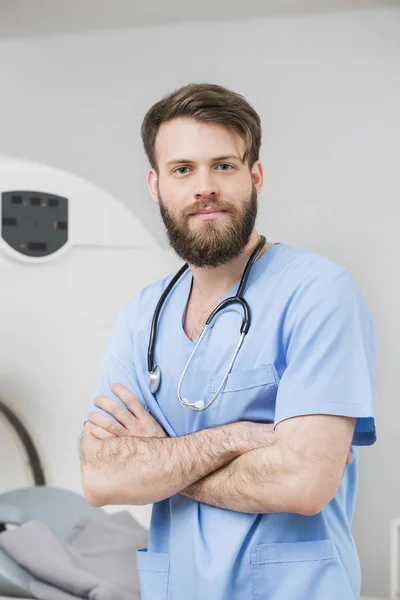 Male Doctor Standing Arms Crossed In Examination Room