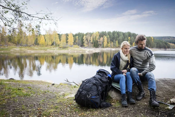 Pareja con mochila relajante en la orilla del lago durante el camping — Foto de Stock