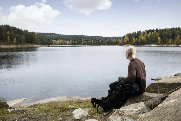Людина, що сидить на рок, насолоджуючись видом на озеро — стокове фото