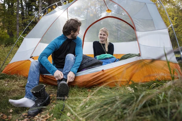 Homem vestindo botas enquanto olha para a mulher na tenda — Fotografia de Stock