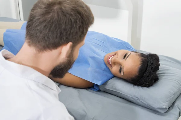 Paciente feminina olhando para o médico masculino examinando-a na clínica — Fotografia de Stock