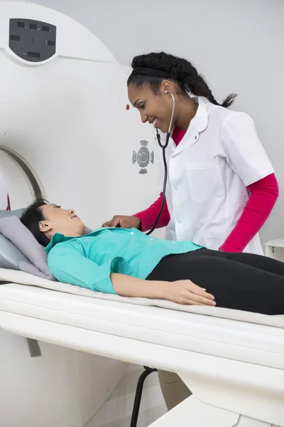 Médico examinando a mujer con estetoscopio antes de tomografía computarizada —  Fotos de Stock