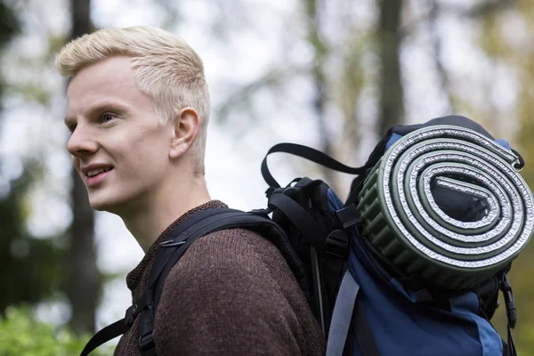 Homem com mochila e tapete rolou caminhadas na floresta — Fotografia de Stock