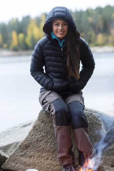 Mulher usando jaqueta de inverno durante o acampamento à beira do lago — Fotografia de Stock