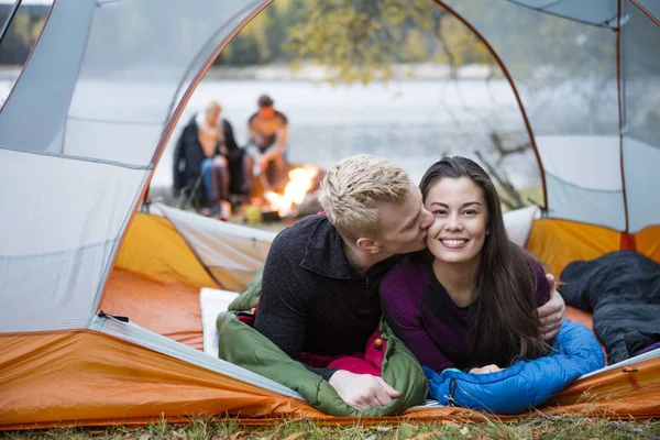 Jeune homme embrasser femme tandis que couché dans la tente — Photo