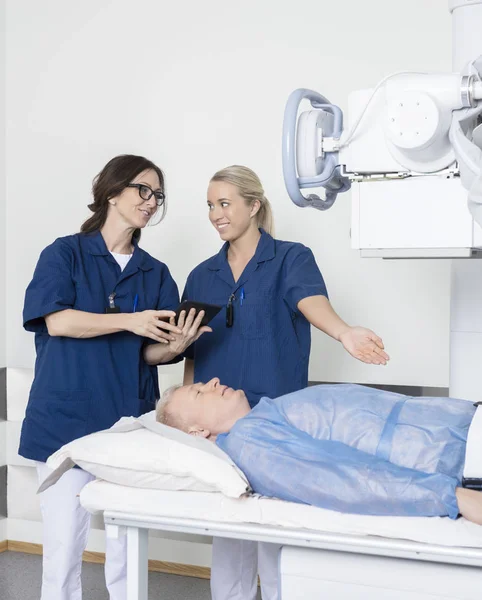 Radiologo Gesturing Verso paziente mentre collega Holding Di — Foto Stock