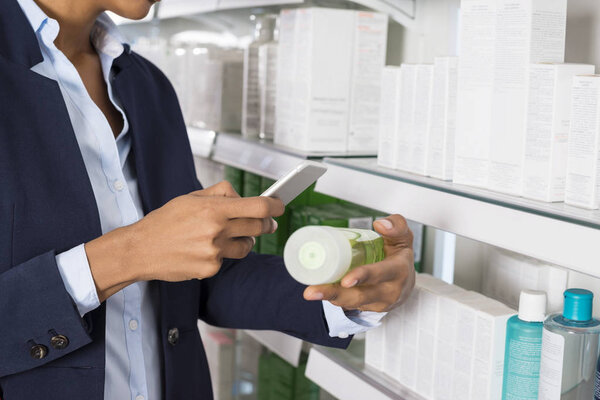 Businesswoman Scanning Products Barcode Through Smart Phone
