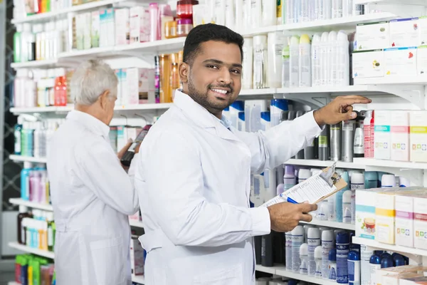 Улыбающийся химик считает акции с коллегой по аптеке — стоковое фото