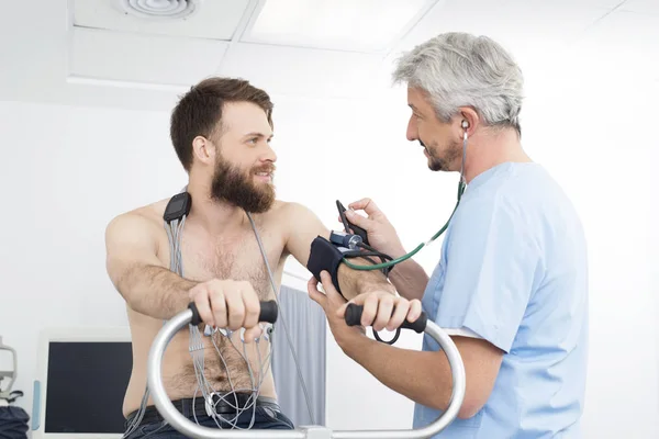 Médico midiendo la presión arterial del paciente en bicicleta en el hospital — Foto de Stock