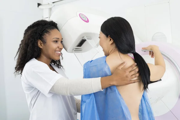 Feliz doctor asistiendo a una mujer sometida a prueba de rayos X de mamografía —  Fotos de Stock