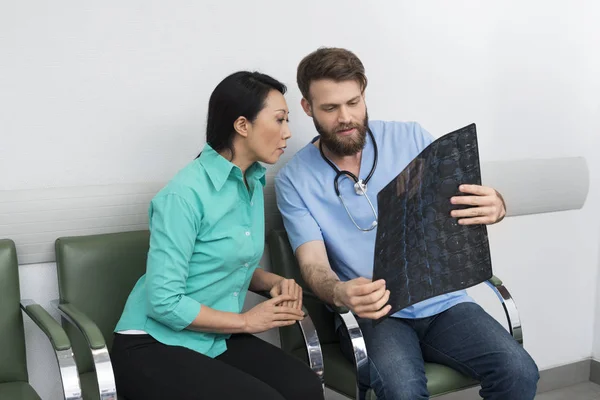 Doctor explicando rayos X al paciente en el vestíbulo del hospital — Foto de Stock