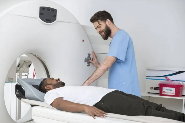 Médico jovem prestes a iniciar a tomografia computadorizada no homem no hospital — Fotografia de Stock