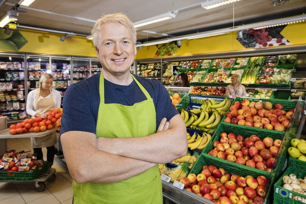Verkäufer steht mit von Früchten gekreuzten Armen im Geschäft — Stockfoto