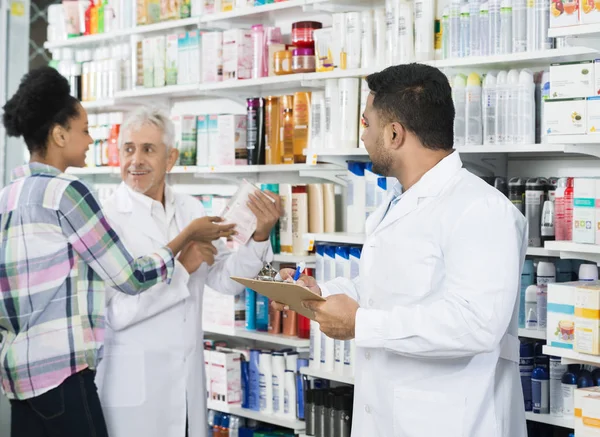 Chemist segurando prancheta enquanto olha para Colega e Custome — Fotografia de Stock