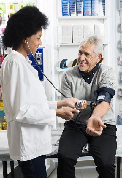 Посміхаючись медсестра перевіряє пацієнтів кров'яний тиск — стокове фото