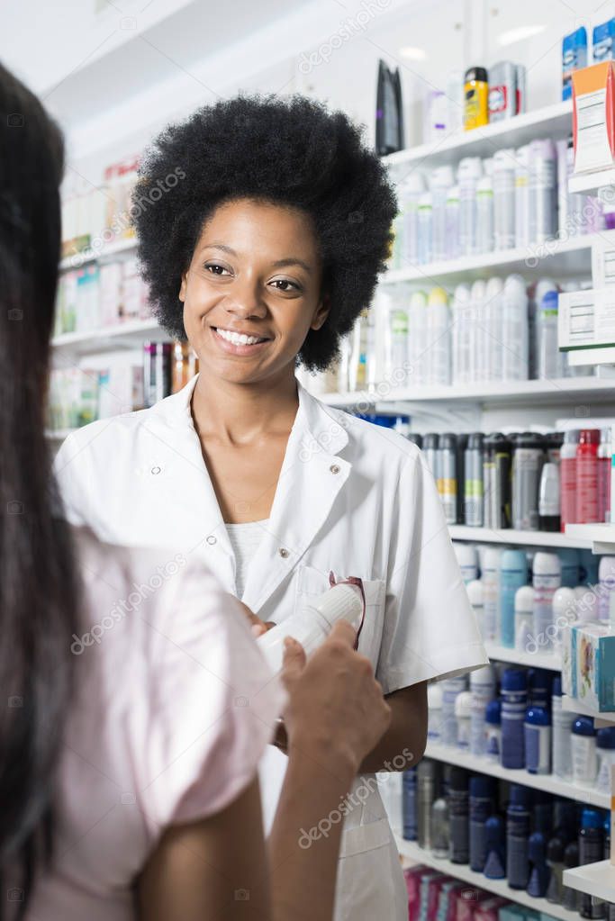 Female Pharmacist Showing Product To Customer In Pharmacy