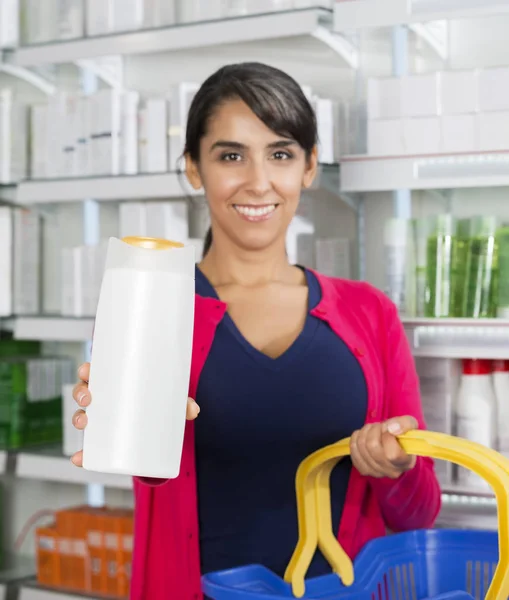 Клієнт показує пляшку шампуню в аптеці — стокове фото