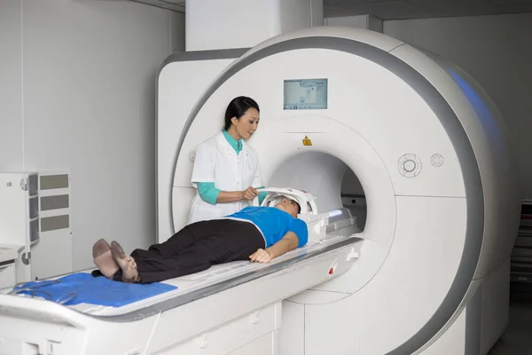 Medico che fissa la maschera al paziente che giace sulla macchina di scansione CT — Foto Stock