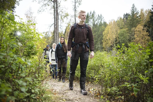 Senderista masculino con amigos caminando por sendero forestal — Foto de Stock