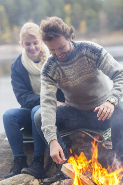 幸福的夫妇坐在篝火上湖岸 — 图库照片