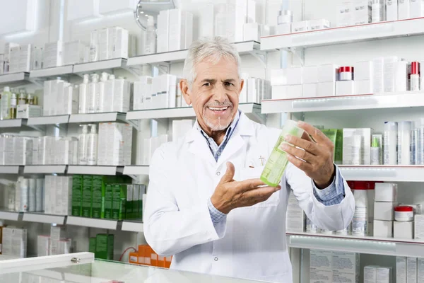 Впевнений фармацевт посміхається тримаючи продукт в фармації — стокове фото