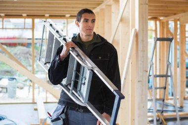 Merdiven inşaat sahasında taşıyan bir marangoz