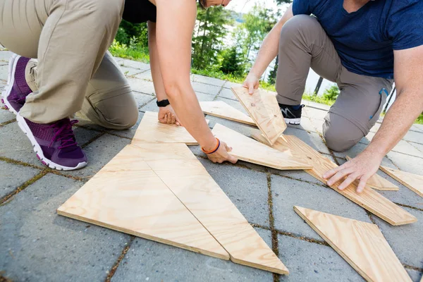 Low Section Of Friends Solving Wooden Planks Puzzle On Patio — Stock Photo, Image