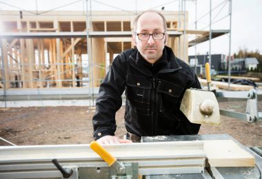 Tablo kullanarak kendine güvenen erkek marangoz tahta kesmek için gördüm