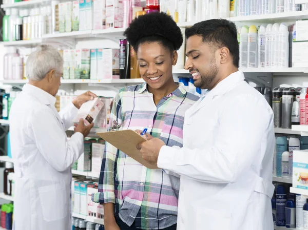 Químico explicando prescrição ao cliente na farmácia — Fotografia de Stock