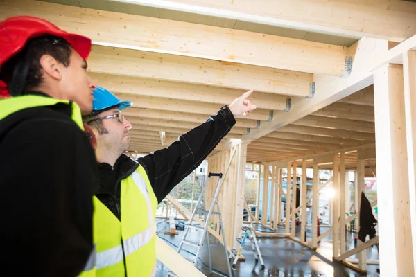 Charpentier pointant sur le faisceau de toit tout en se tenant par collègue — Photo