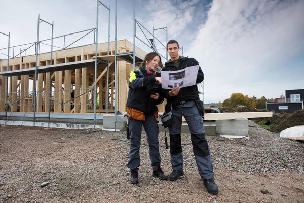 Snickare som diskuterar om Plan mot ofullständiga byggnad — Stockfoto